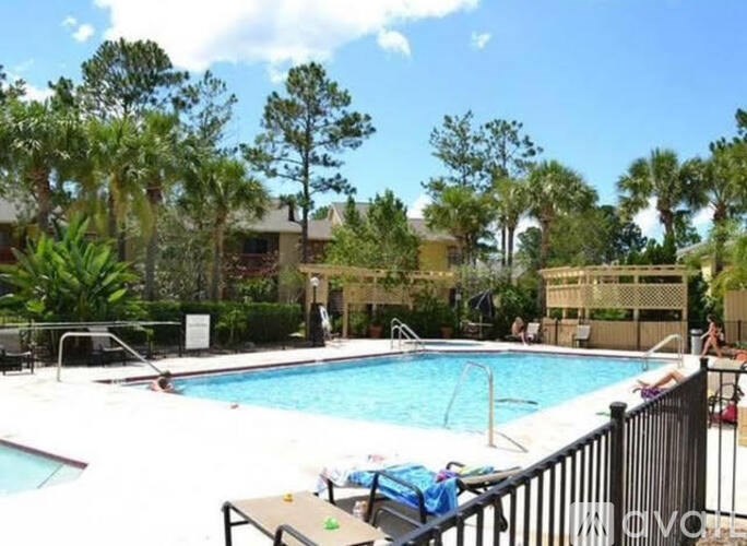 A pool surrounded by trees and a fence.
