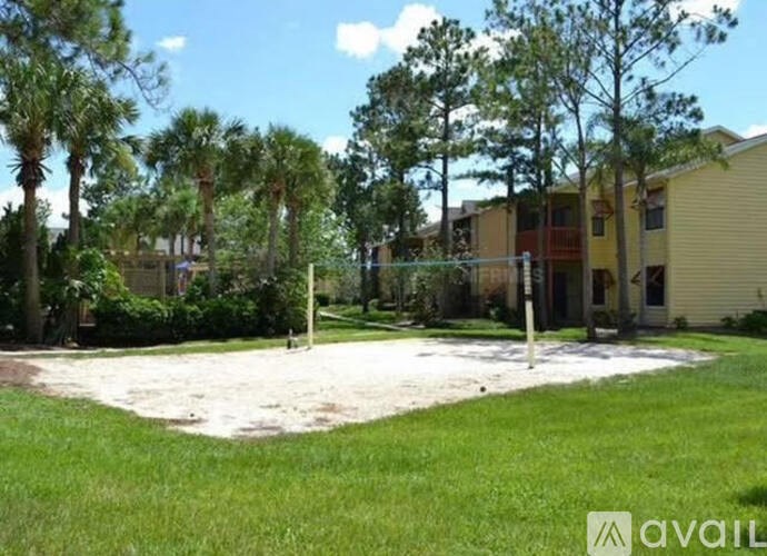 A sandy area in front of a building surrounded by trees.
