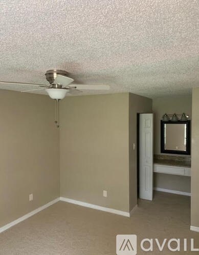 A room with a fan and a mirror on the wall.