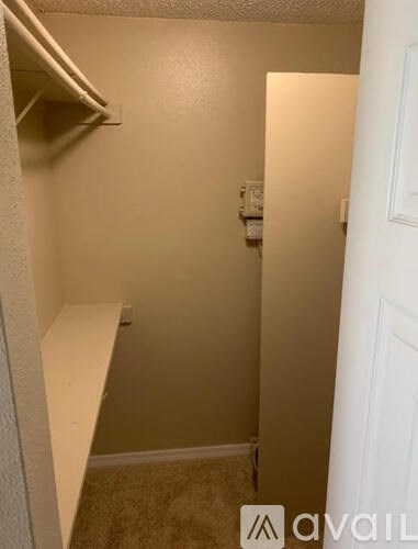 A small, empty room with a white door and a white shelf on the wall.