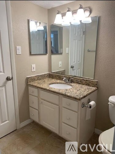 A bathroom with a granite countertop and a large mirror above the sink.