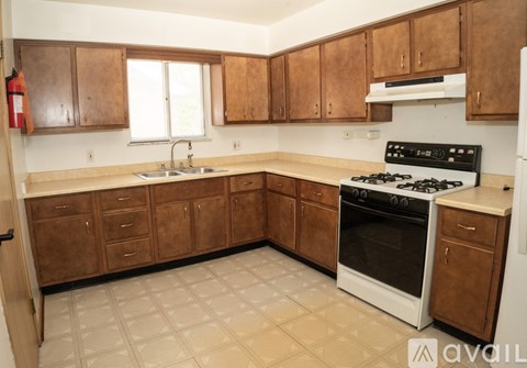 A kitchen with wooden cabinets and a white stove top oven.