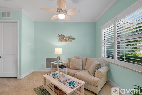 A living room with a couch, a table with a lamp, and a ceiling fan.