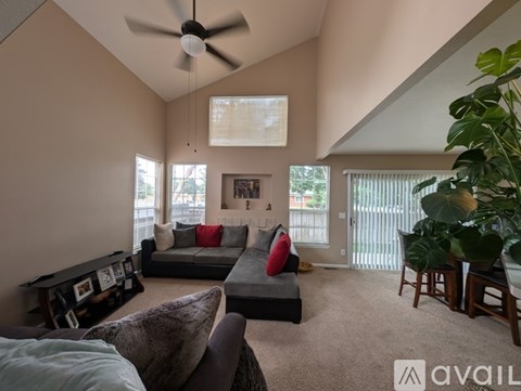 A living room with a grey couch and a ceiling fan.