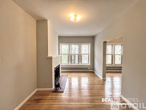 A room with a wooden floor and a window overlooking a balcony.