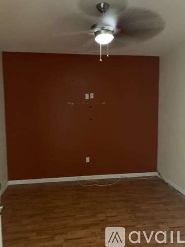 A room with a ceiling fan and wooden flooring.