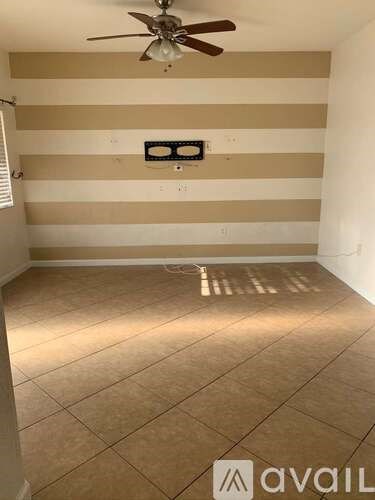 A room with a ceiling fan and striped wallpaper.