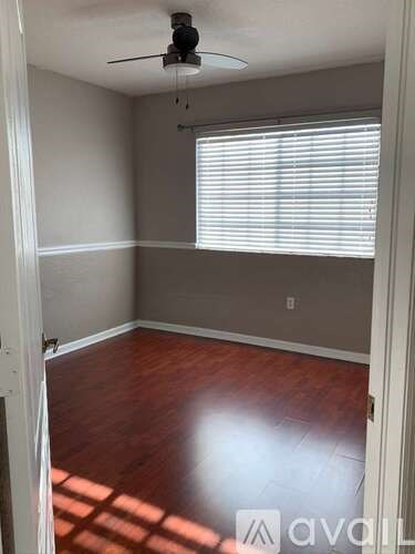 A room with a ceiling fan and a window with blinds.