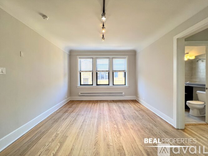 A room with wooden flooring and a window with blinds.