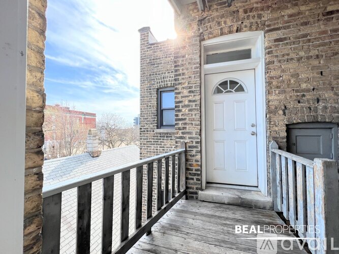 A balcony with a white door and a brick wall.