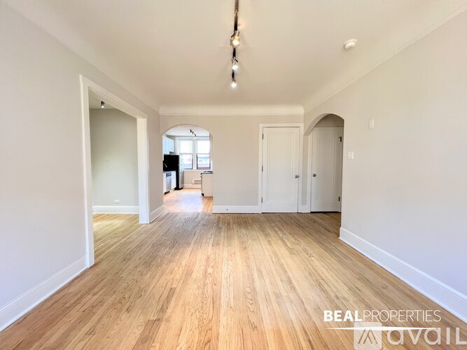 A spacious room with wooden flooring and white walls.