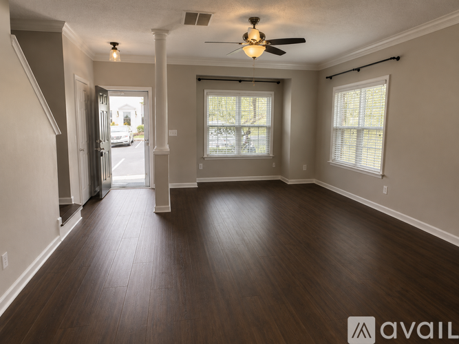 A spacious room with wooden flooring and a ceiling fan.