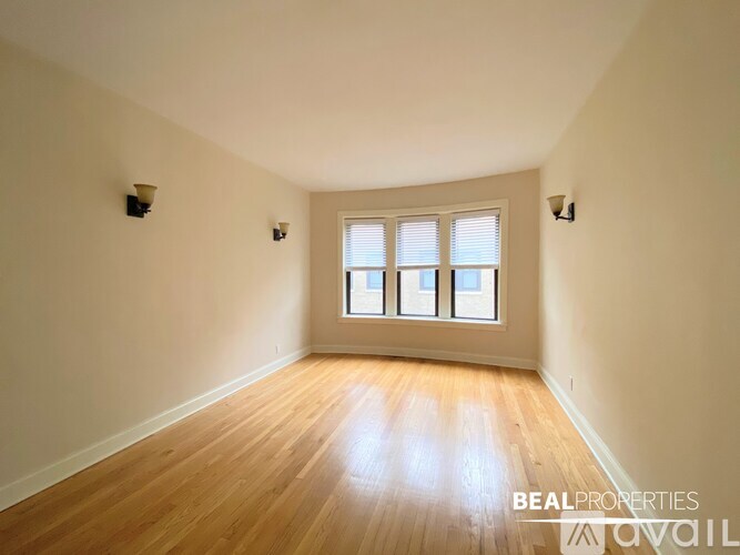 A room with wooden floors and a window with blinds.