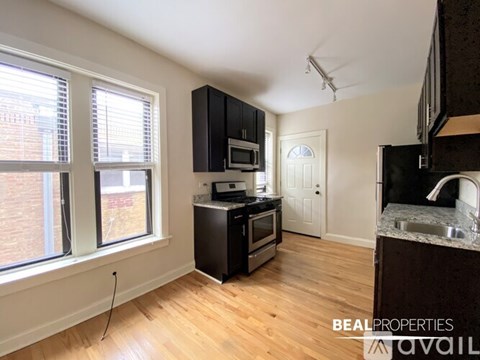 A kitchen with black cabinets and a wooden floor.