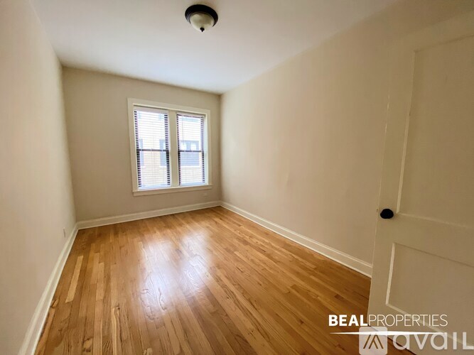 A room with wooden flooring and a window with blinds.
