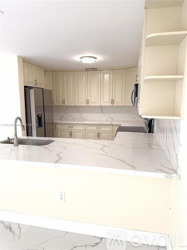 A kitchen with white cabinets and marble countertops.