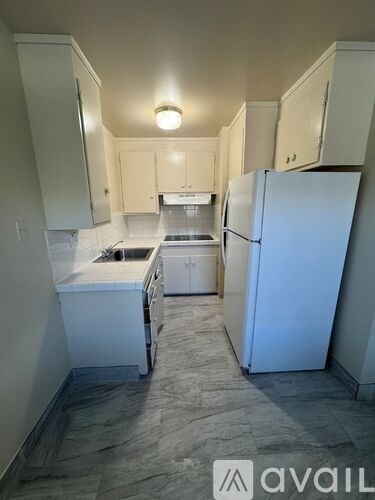 A kitchen with a white fridge and white cabinets.