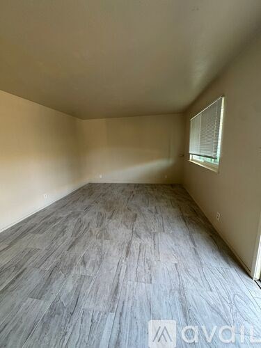 A room with a window and wooden flooring.