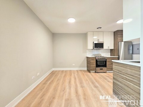 A kitchen with white cabinets and a wooden floor.