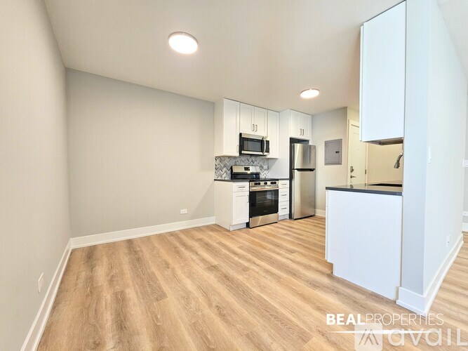 A kitchen with white cabinets and a wooden floor.
