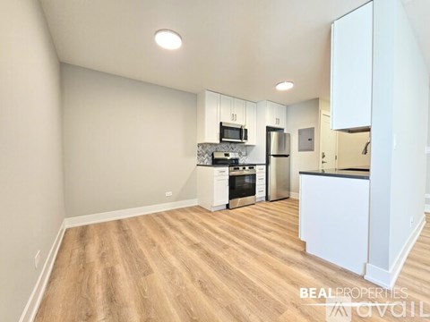 A kitchen with white cabinets and a wooden floor.