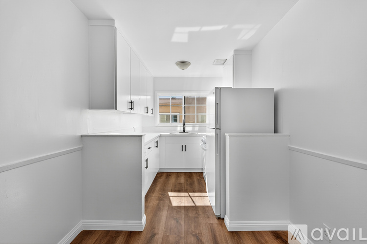 A kitchen with white cabinets and a white fridge.