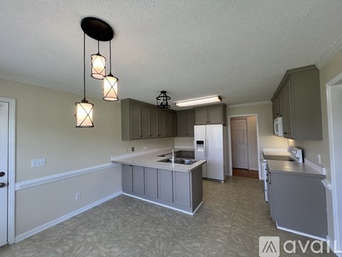 A kitchen with a sink, refrigerator, and cabinets.
