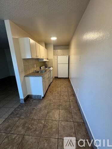 A kitchen with white cabinets and brown tiled floors.