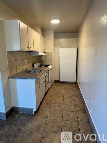 A kitchen with white cabinets and a white refrigerator.