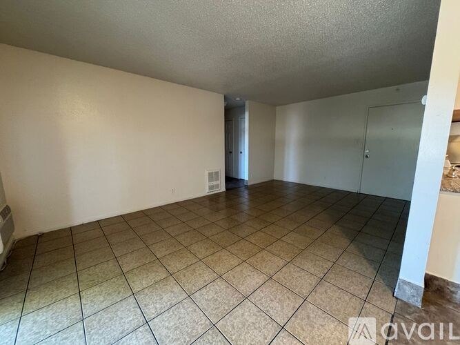A spacious room with tiled flooring and a glass door leading to another room.