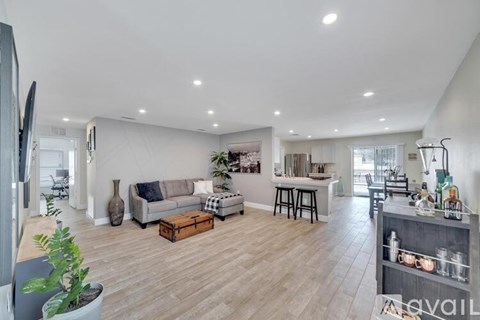 A spacious living room with a grey sofa and wooden flooring.