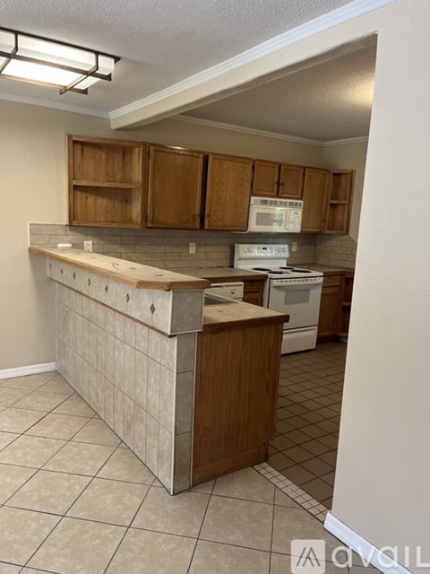 A kitchen with a white stove top oven and wooden cabinets.