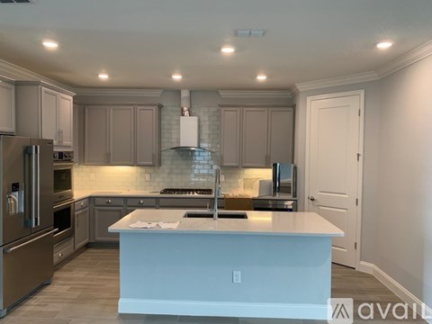 A kitchen with a white island and stainless steel appliances.