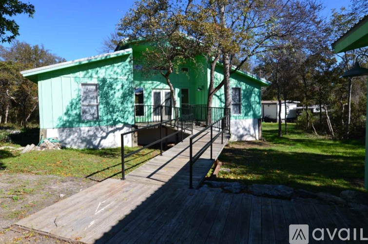 A green house with a deck in front.