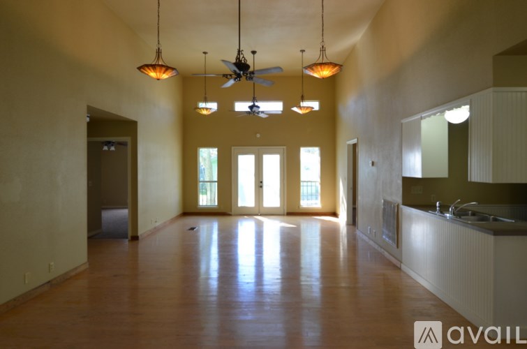 A large empty room with a fan and hanging lights.