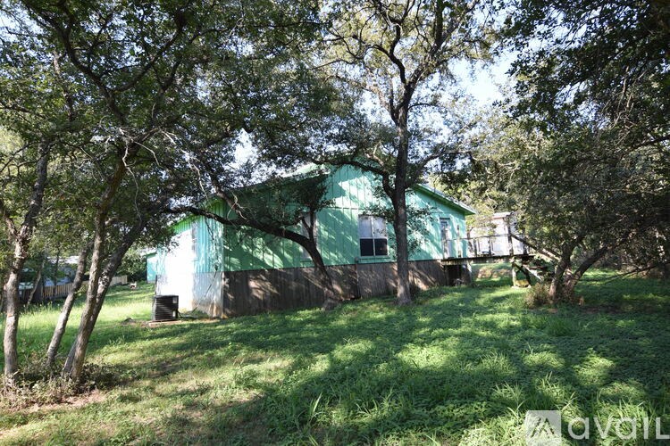 A green building with a white roof is surrounded by trees.