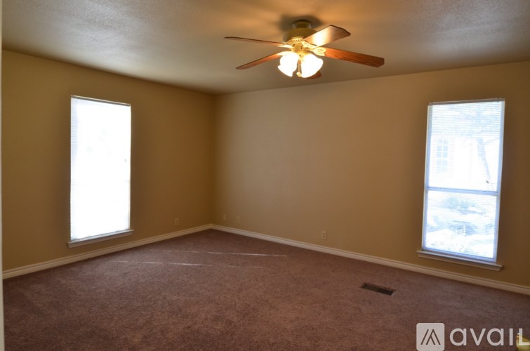 A room with a ceiling fan and two windows.