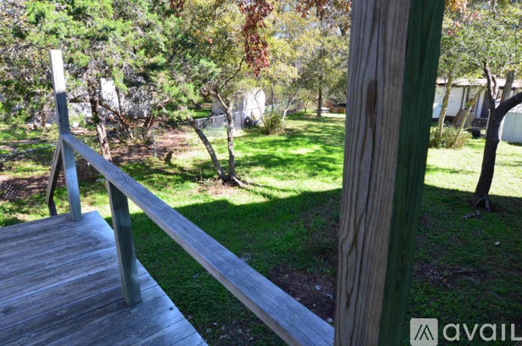 A wooden deck with a metal railing overlooks a grassy area.