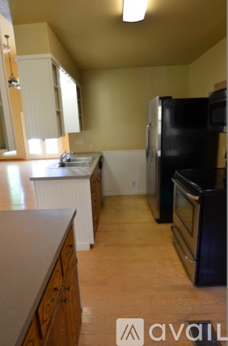 A kitchen with wooden floors and black appliances.
