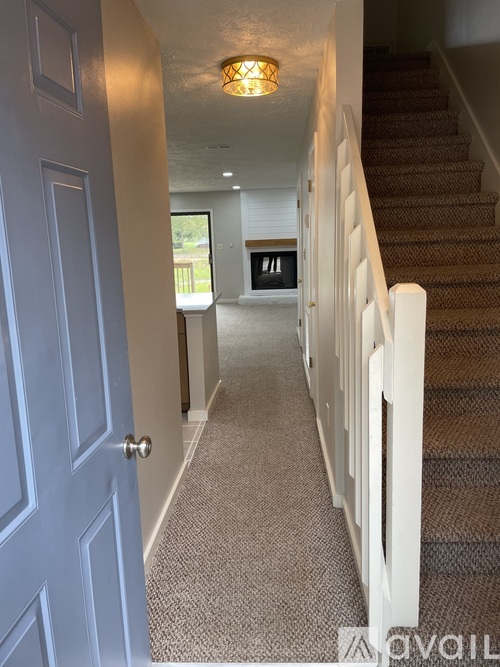 A hallway with a staircase and a door.