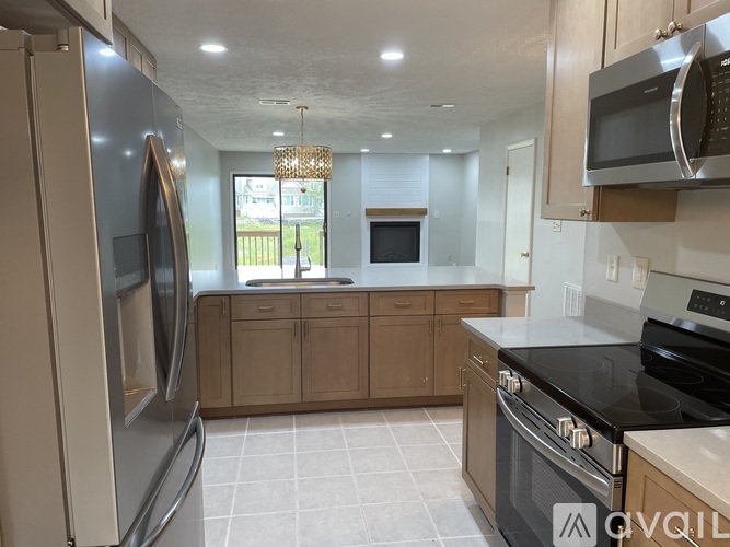 A kitchen with a refrigerator, microwave, oven, and cabinets.