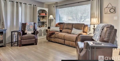 A living room with brown leather furniture and a wooden floor.