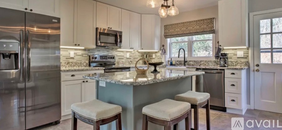 A kitchen with a refrigerator, microwave, and a counter with a sink.