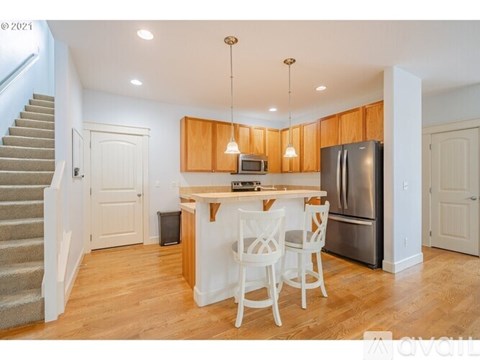 A kitchen with wooden cabinets and a stainless steel refrigerator.