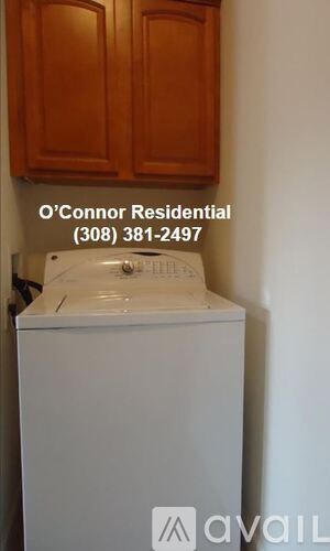 A white dishwasher is in a kitchen with wooden cabinets.
