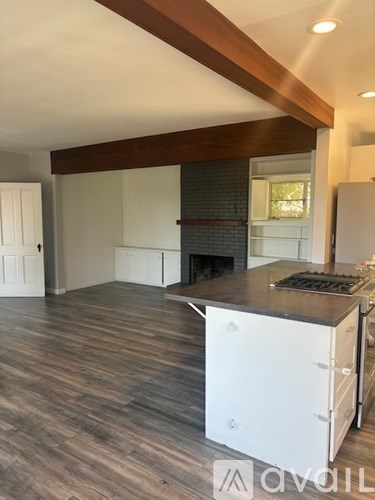 A kitchen with a white stove top oven and wooden flooring.