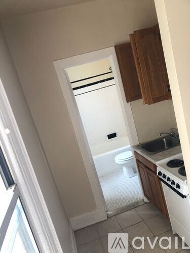 A small kitchen with a sink, stove, and toilet.