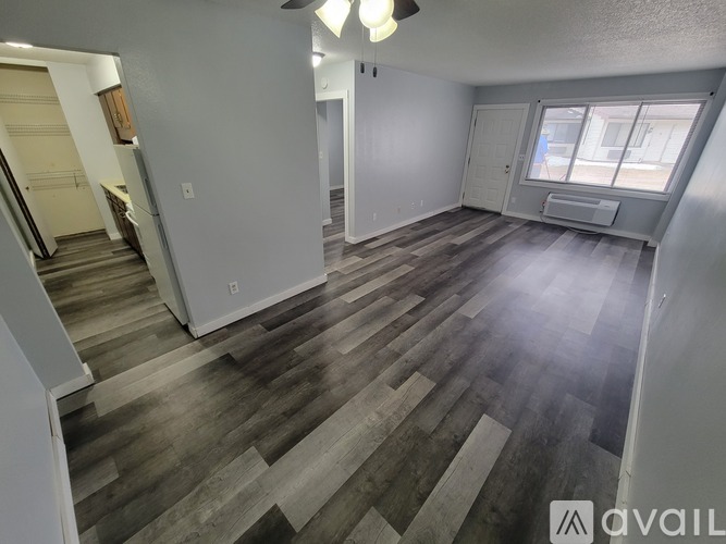 A spacious room with wood flooring and a ceiling fan.