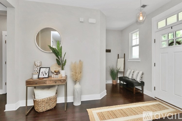 A white hallway with a round mirror and a bench.