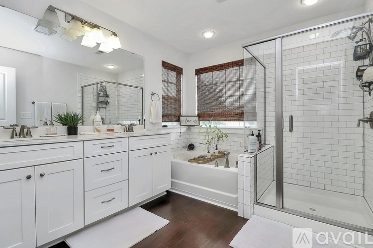 A bathroom with a white tile shower and a white bathtub.